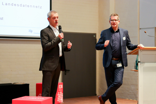 Auf dem Bild sind der Stellvertretende IT.Niedersachsen Geschäftsführer Michael Breest und EWE-TEL Geshäftsführer Ludwig Kohnen zu sehen. Sie stehen auf der Bühne bei der WAN-3.0-Kundenveranstaltung.