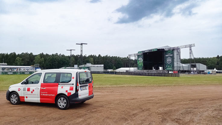 Ein Fahrzeug von IT.Niedersachsen auf dem Gelände des Hurricane-Festivals, im Hintergrund ist die Hauptbühne zu sehen.