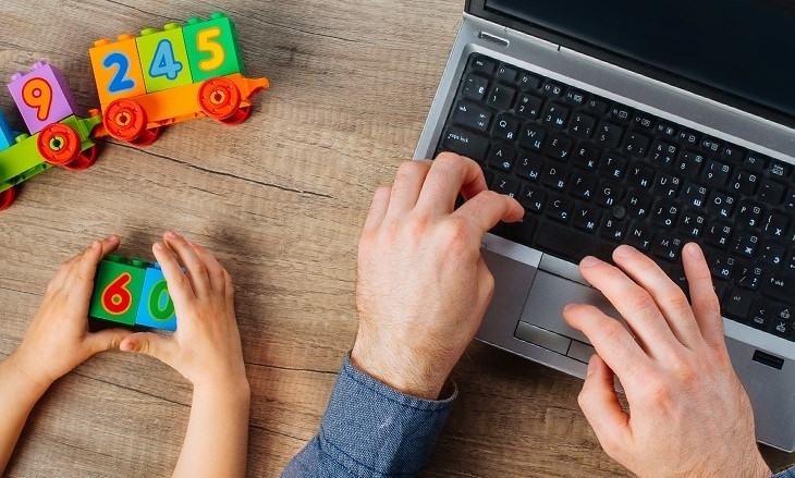 Laptop und daneben zwei Kinderhände, die spielen