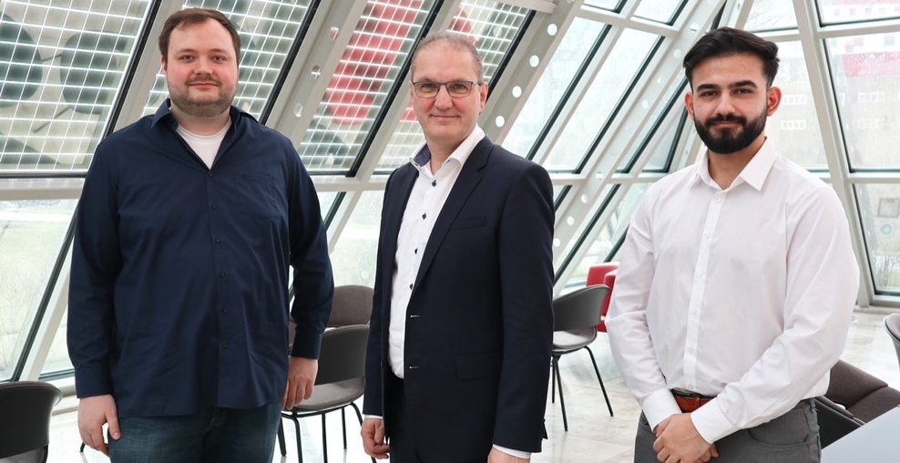 Das Foto zeigt Staatssekretär Stephan Manke sowie die beiden Auszubildenden Phillipp Engelking und Katip Arslan. Sie stehen nebeneinander und lächeln in die Kamera.
